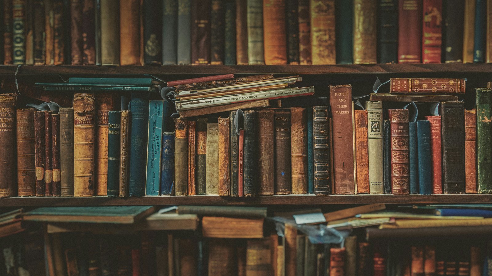 A stack of books beside a reading lamp at night